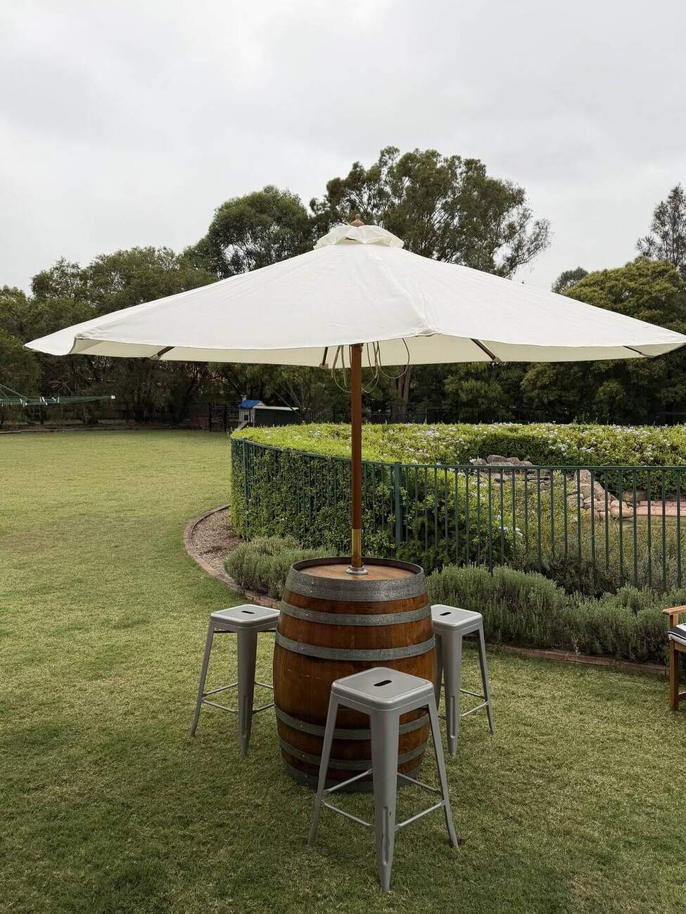 Wine barrel paired with bar stools and a market umbrella for casual lawn seating